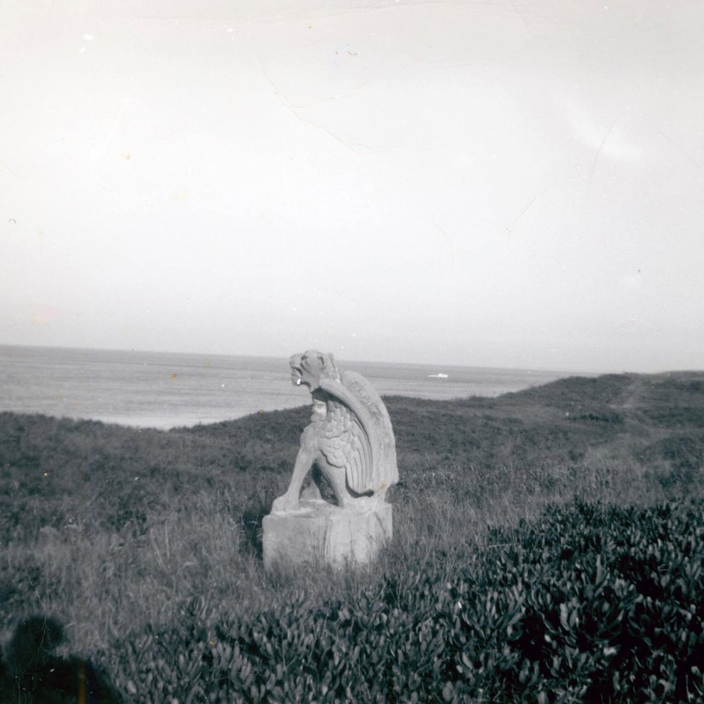 A black and white image of a stone statue of a creature with wings