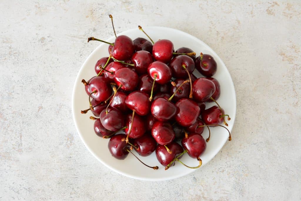 A bowl of cherries, a memory of the joy-filled journey, sitting on a white table.