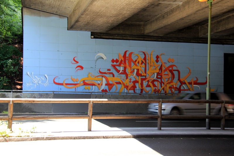 Red-and-orange calligraffiti on a blue tiled wall
