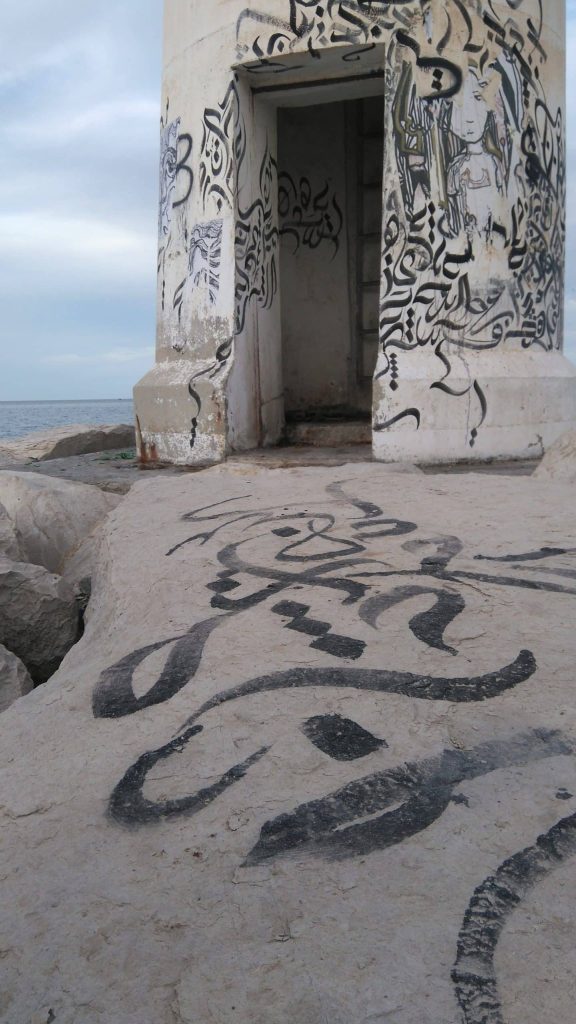The image shows calligraffiti at the fishing port in Sayada. A fragment of the sea and the sky could also be seen in the background.
