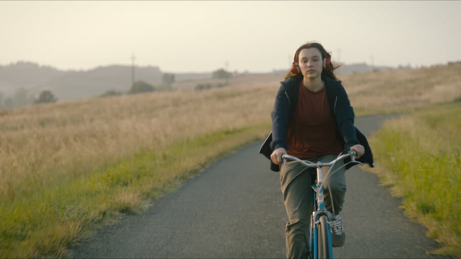 Sara Toscano riding a bike with headphones on for "Feel My Voice."