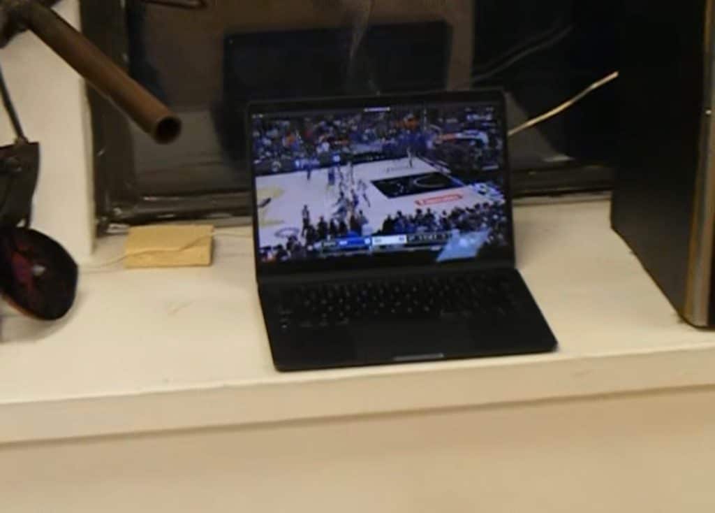 Grainy hand-held camera footage of the Knicks' NBA finals game playing on a MacBook, during the gallery opening.