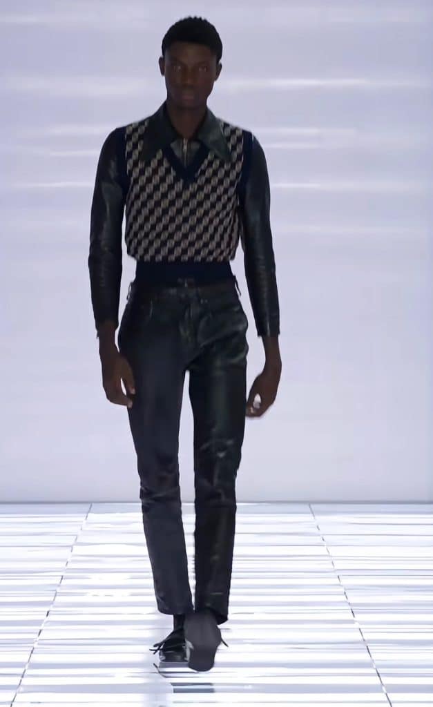 A screengrab from the Prada runway featuring a skinny silhouette and tight fitting vest.