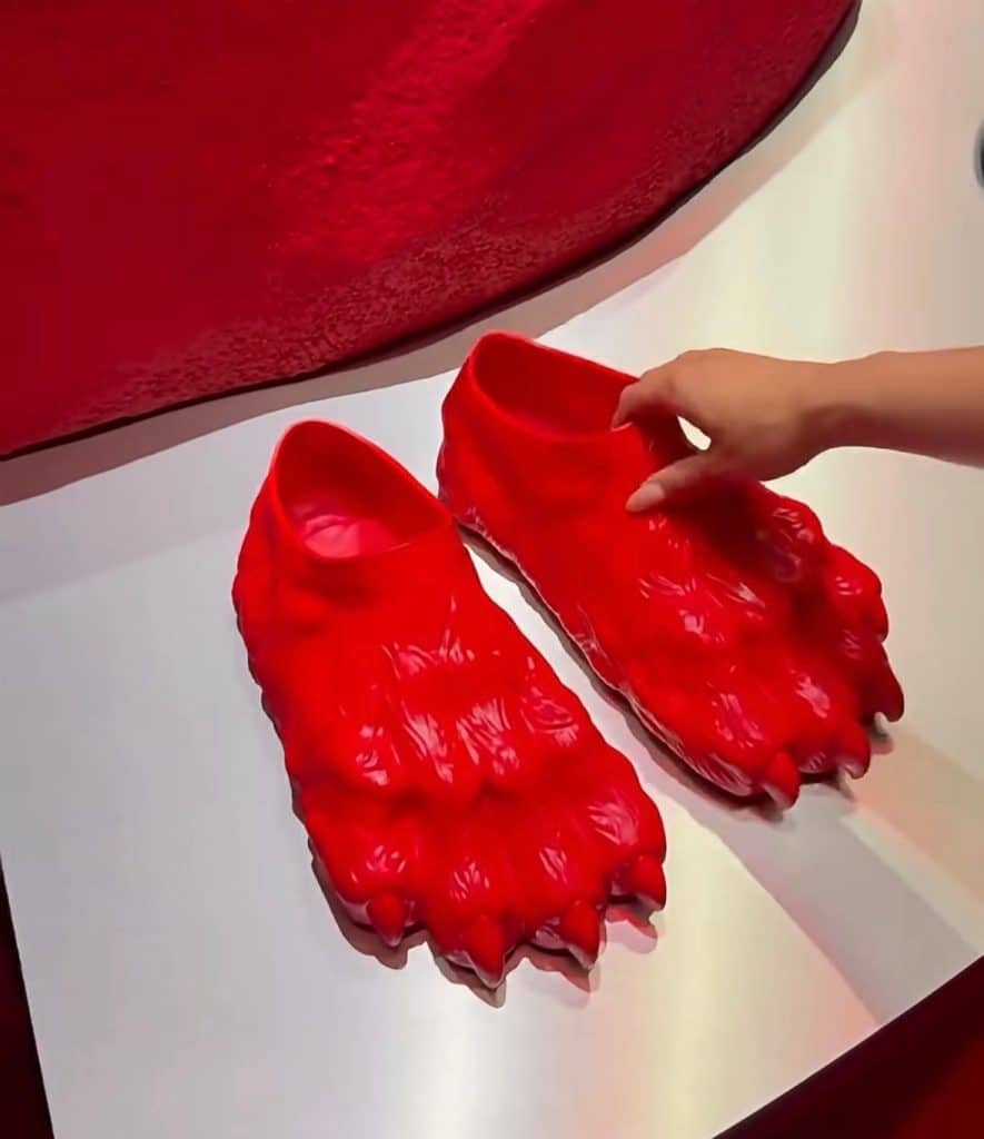 Avant garde clogs that are completely red and carved into the shape of a bears claw.