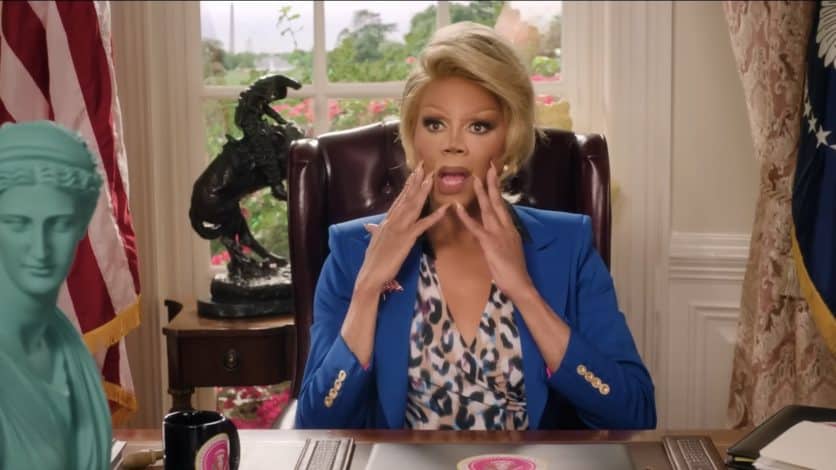 RuPaul as President looking shocked sitting at her desk in the White House.