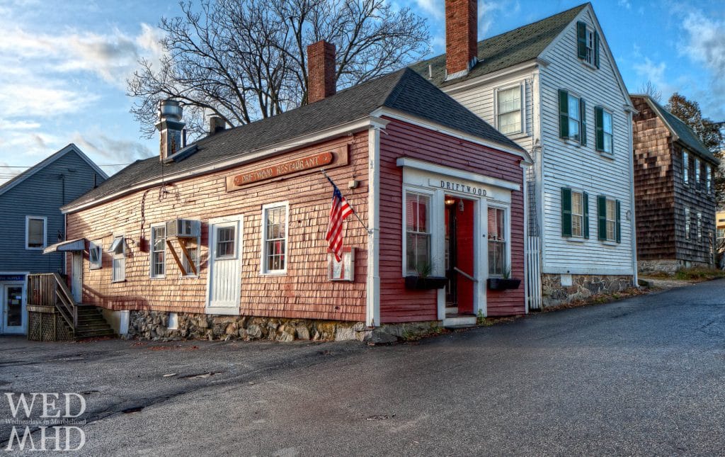 A side street view of the red shingled building of the Driftwood Restaurant
