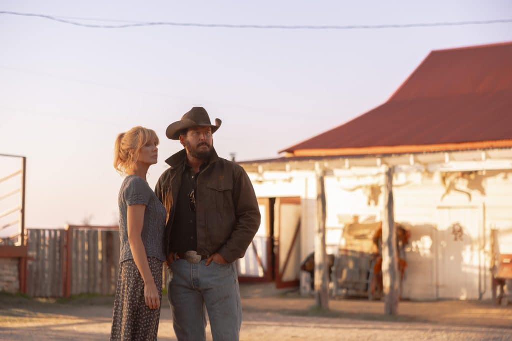 Kelly Reilly and Cole Hauser in Dutton Ranch, standing next to each other outside a property