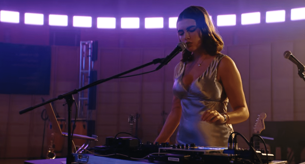A woman singing into a microphone and performing with a DJ set