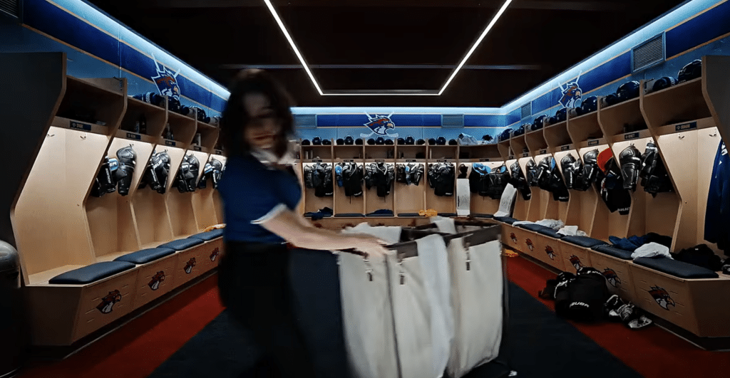A girl dragging a white bin in a men's locker room