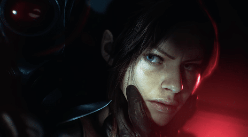 Claire Redfield apprehended by a hand offscreen, expression pinched as she glares at her assailant. The lighting is slightly red but mostly dark, furthering the aura of horror in the upcoming game.