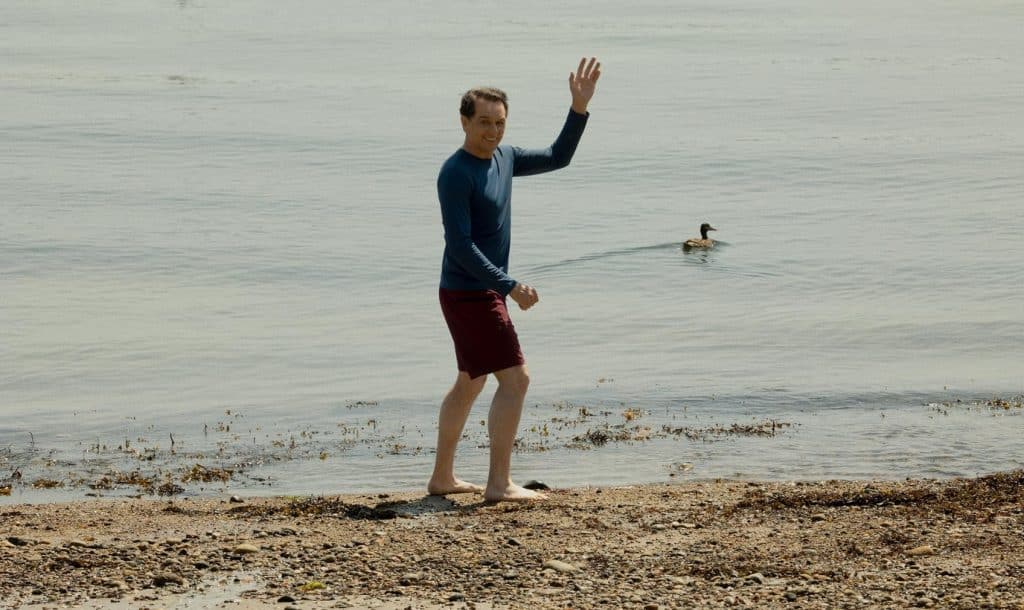 Matthew Rhys as Tom Loftis waving as he goes into the sea.