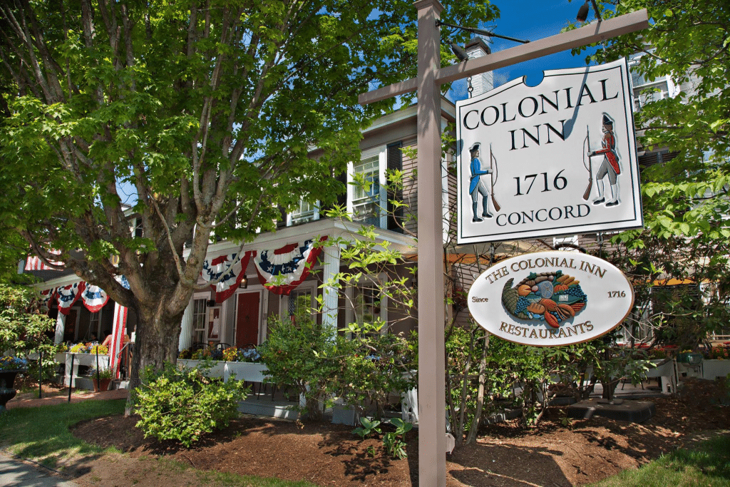 The exterior of the Colonial with two colonial soliders on the sign which says "Colonial Inn, 1716, Concord"
