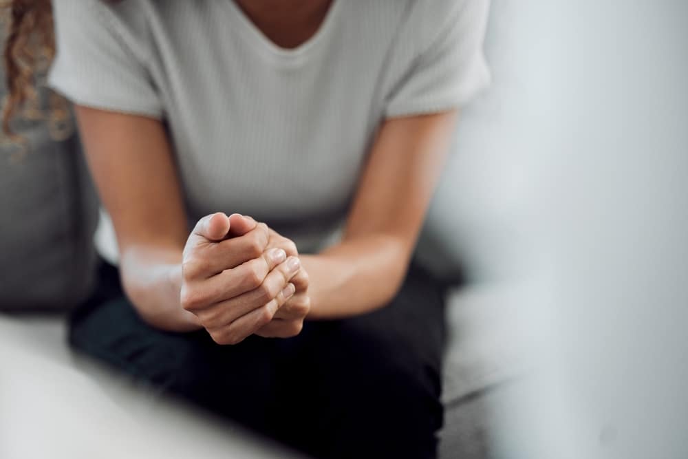 person clasping their hands together while hunched over