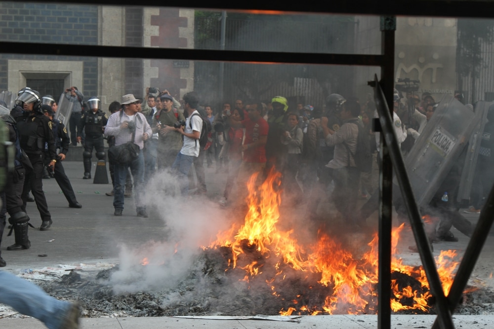 Mexico City, Mexico — April 26, 2015. Protesters ignite a fire during a demonstration over the disappearance of the 43 Ayotzinapa students as police officers attempt to contain the unrest. Credit: Shutterstock picture by JuanAriza1