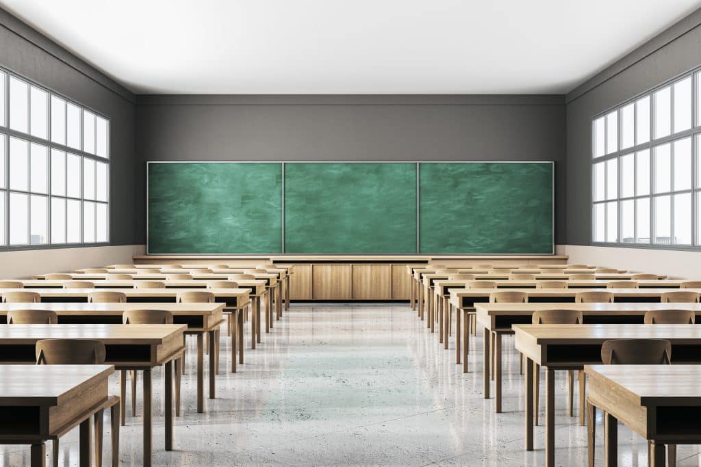 An empty classroom with rows of desks and chairs.