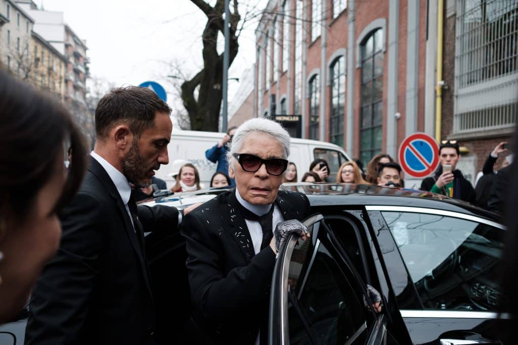 Famed designer, Karl Lagerfeld gets out of a car, sporting his classic mane of white hair.