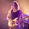 The Vampire Lestat poised in concert, staring down an audience while gripping his guitar.