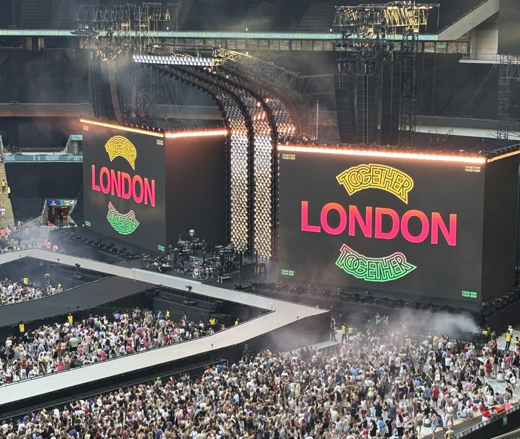London in big pink letters with together together above and below it in yellow and green on a big screen