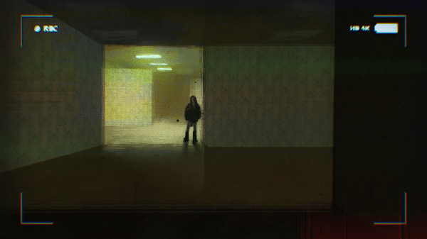 A creepy photo of a dark figure standing at the back of a dimly lit room