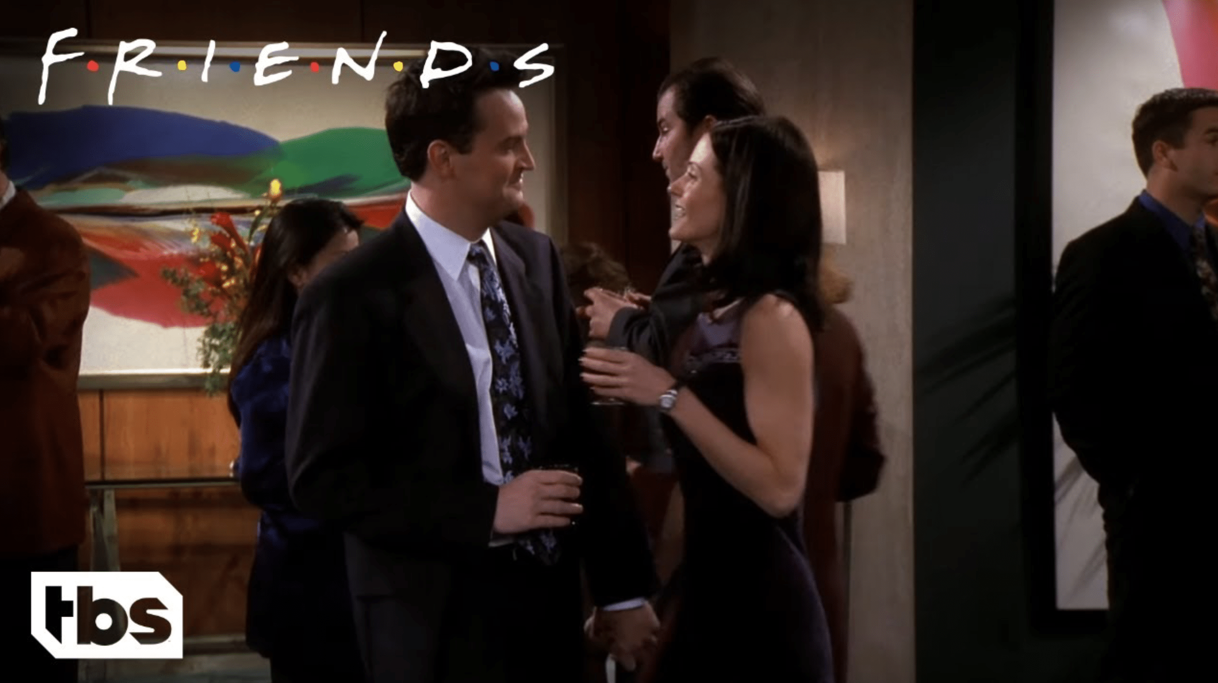A still from the show "Friends" of a couple standing together at a party.