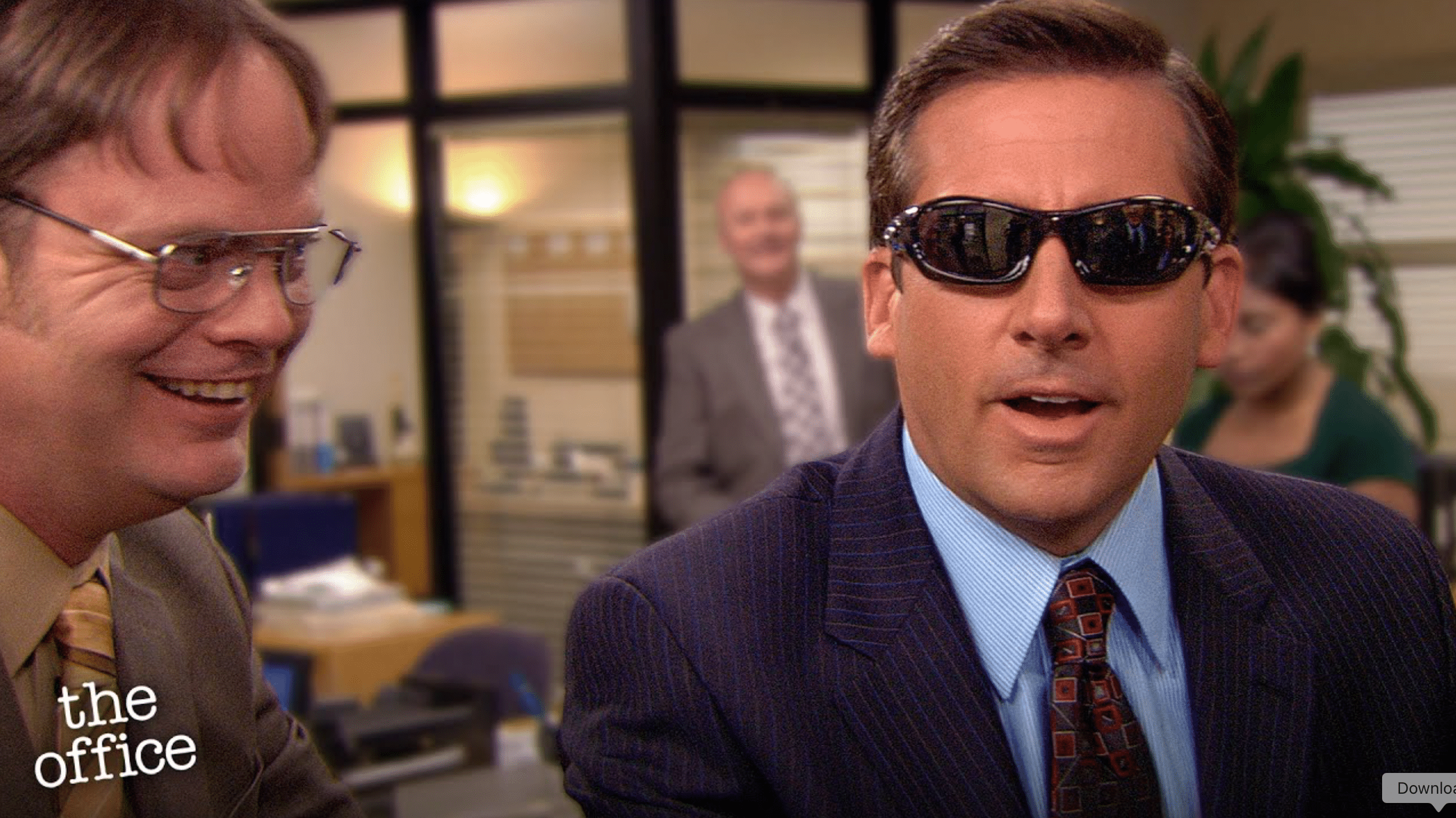 A still from "The Office" of one man wearing sunglasses while another man smiles at him.