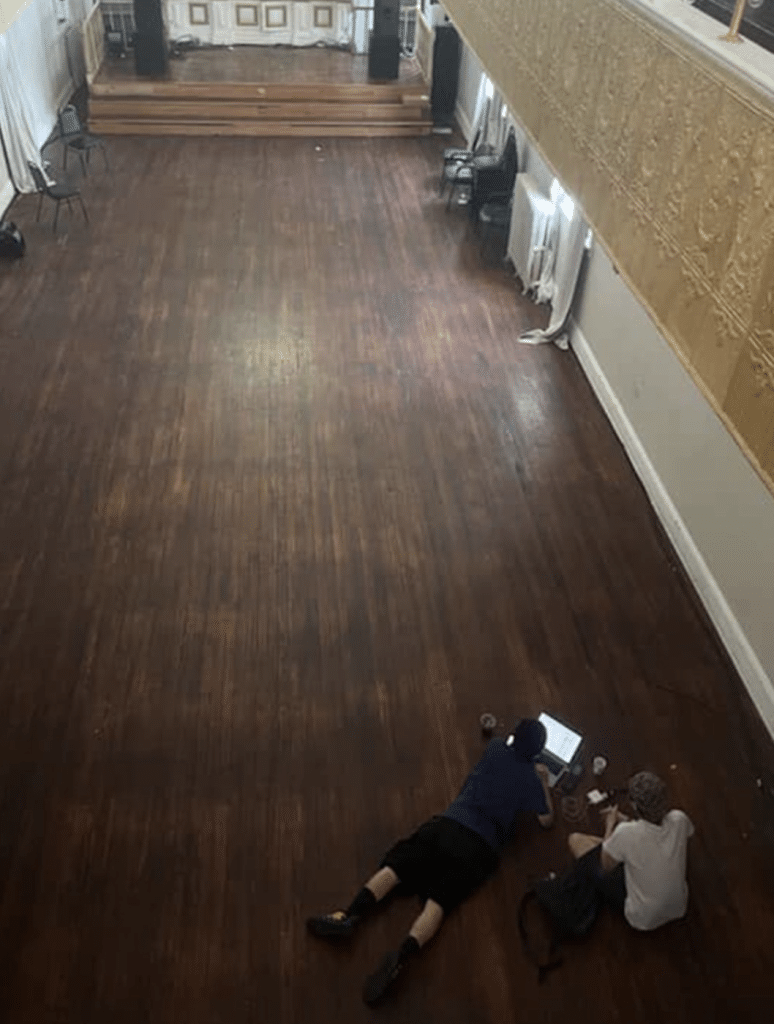 Both curators sitting on the floor of the event space, looking out at the gallery-to-be.