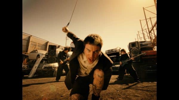 Canadian artist Jutes crouched down in a scrapyard performing for his music video Icarus