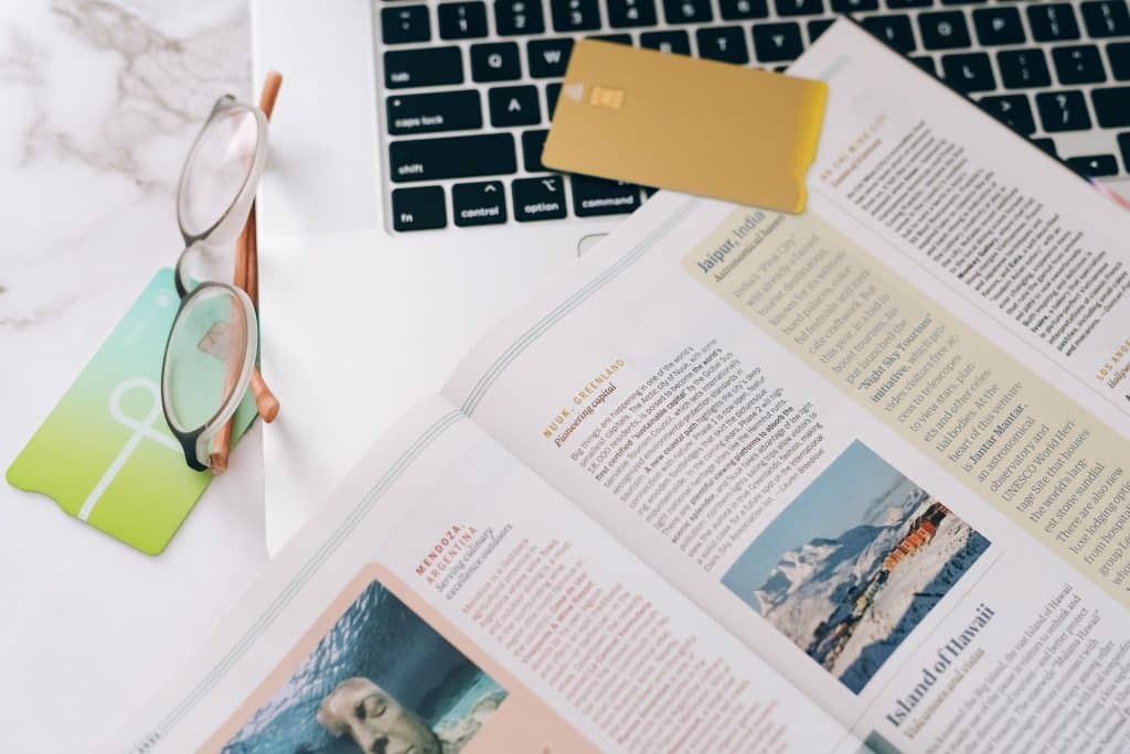 Researching hostels using a laptop and an informative booklet showing different destinations.